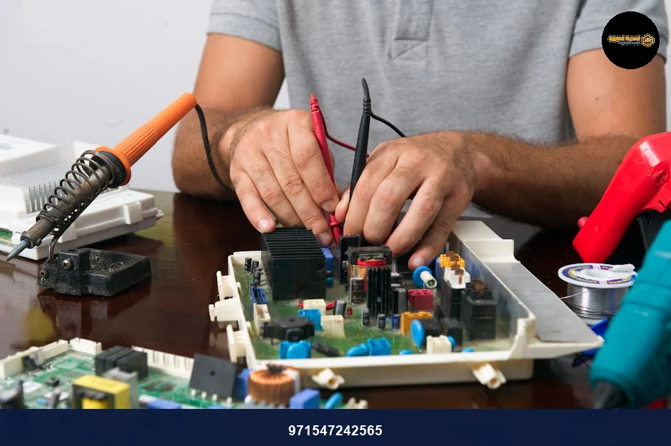 Man working on an electronic circuit board with tools on a table, showing close-up of hands and components.