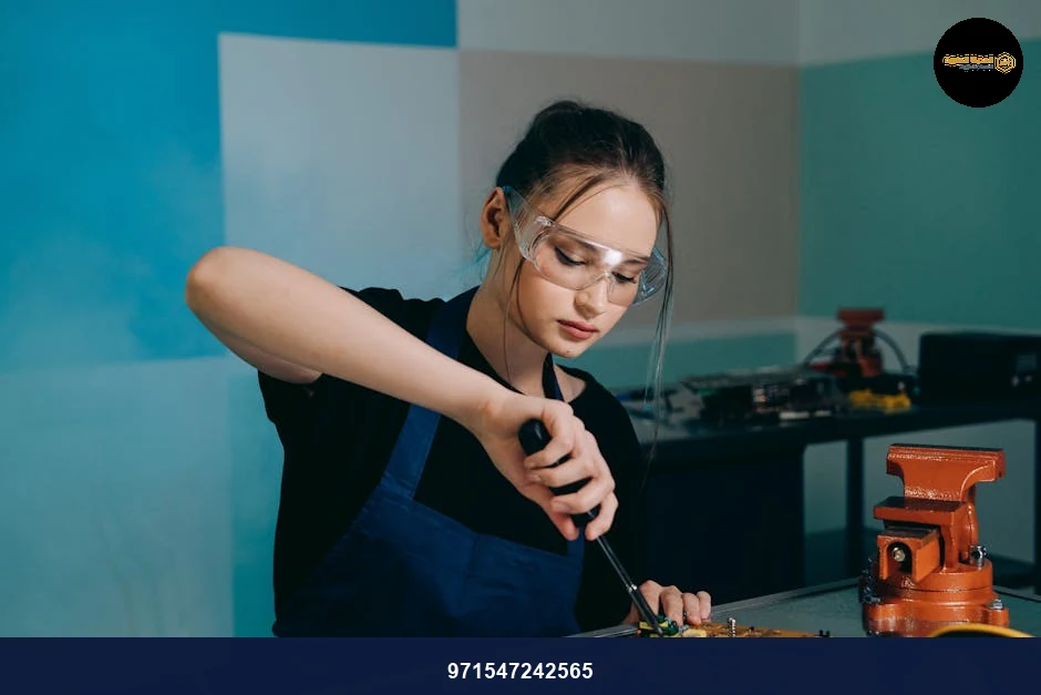 Woman with protective goggles soldering electronic components indoors.