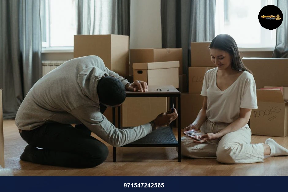 A couple assembling a coffee table amid stacked moving boxes in their new home.