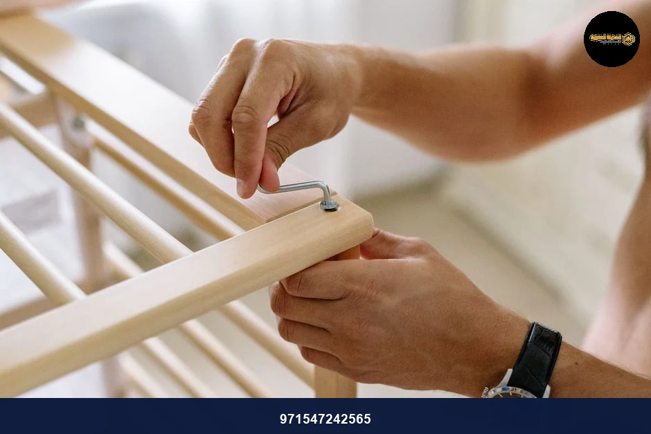 Close-up of a man using an Allen wrench to assemble a wooden baby cot indoors.