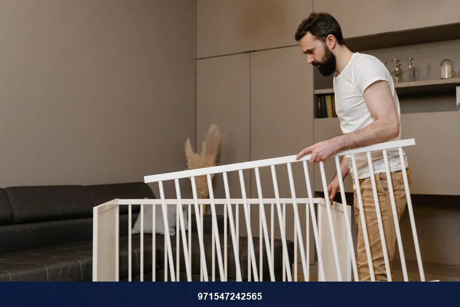 A bearded man assembles a crib in a stylish living room setting. A bearded man assembles a crib in a stylish living room setting.