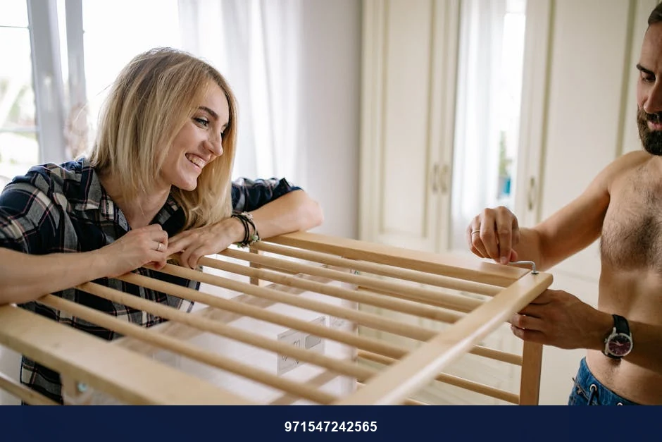 A happy couple assembling a baby crib together in their home. A happy couple assembling a baby crib together in their home.