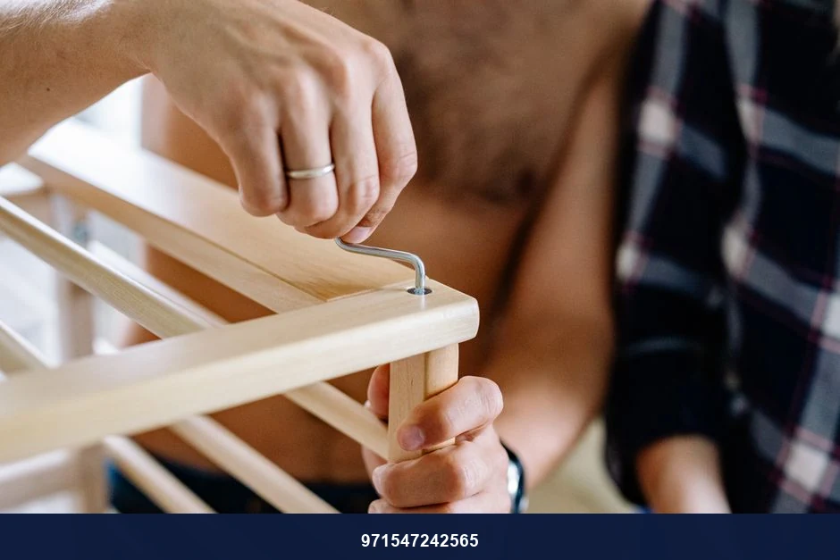 Close-up of a couple working together to assemble a wooden crib indoors. Close-up of a couple working together to assemble a wooden crib indoors.