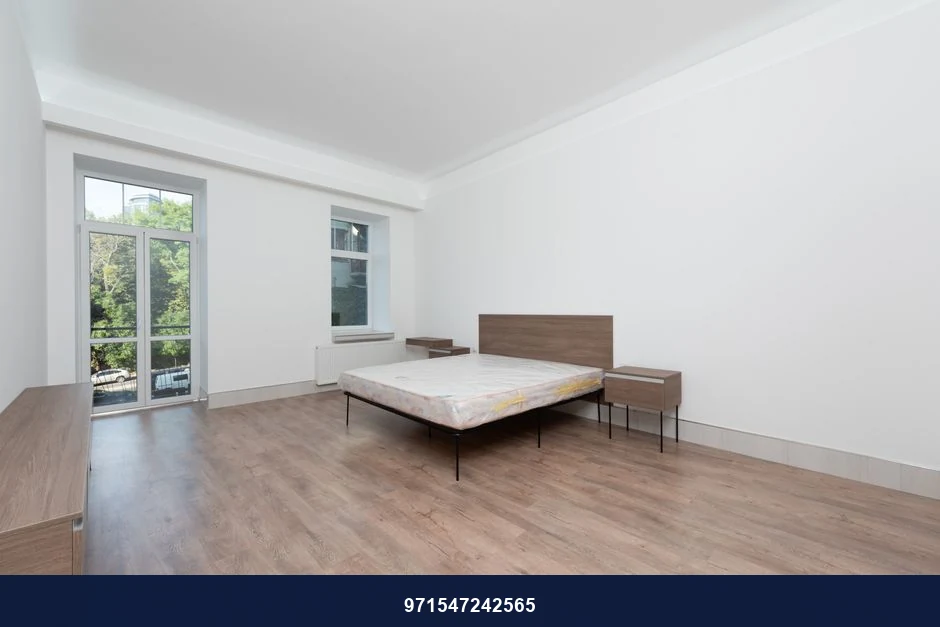 Spacious minimalist bedroom featuring wooden floors and large windows for natural light. Spacious minimalist bedroom featuring wooden floors and large windows for natural light.