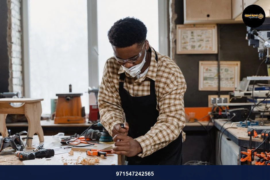 An African American craftsman focuses on woodworking in a well-equipped workshop.