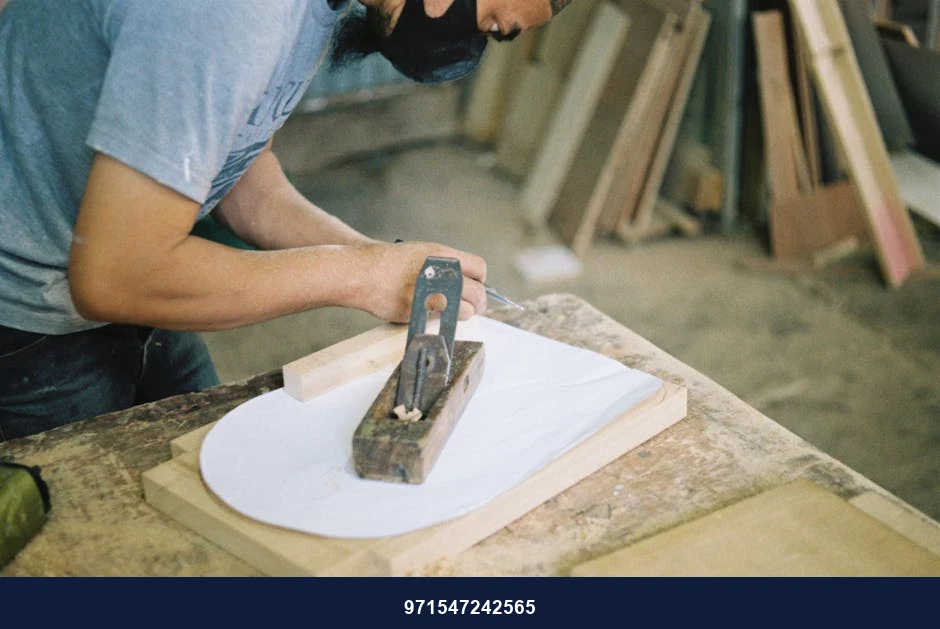 Carpenter woodworking with a hand plane on a wooden surface indoors.