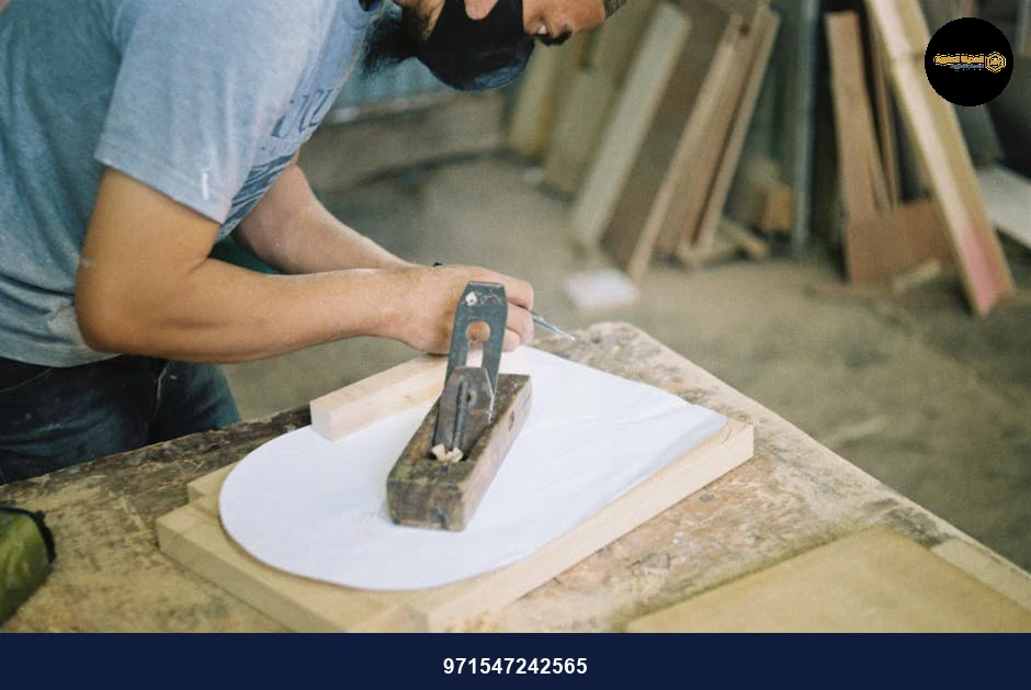 Carpenter woodworking with a hand plane on a wooden surface indoors.