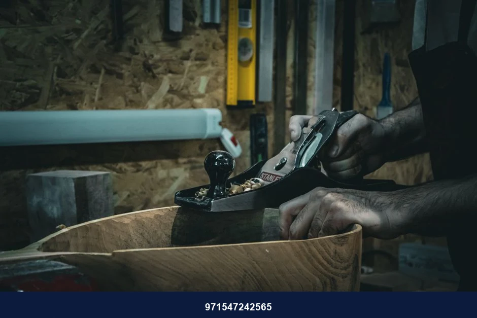 Close-up of craftsman smoothing wood with a hand plane in a workshop, emphasizing skilled carpentry.