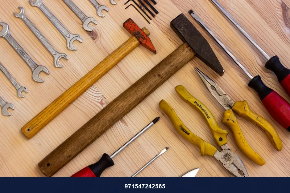 A variety of hand tools including wrenches, screwdrivers, and pliers on a wooden surface.