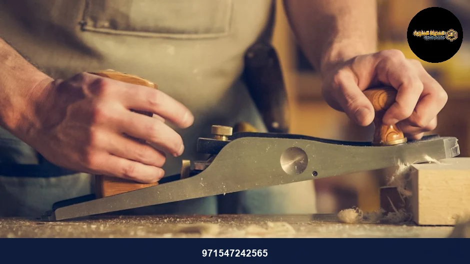 A carpenter skillfully using a hand plane on a wooden surface indoors.