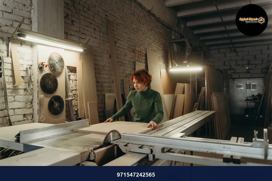 Woman working with wood on a table saw in a carpentry workshop.