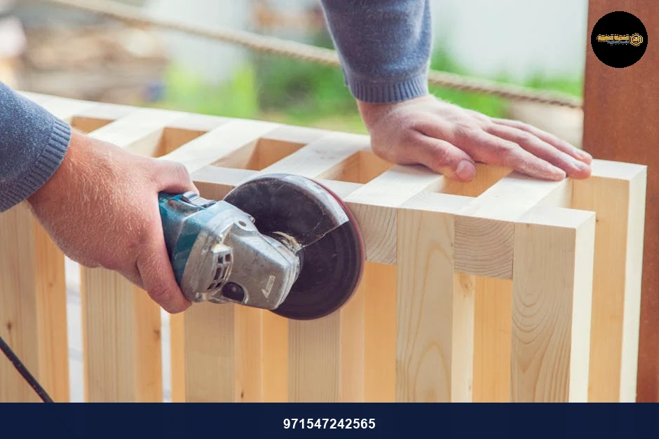 Crop anonymous woodworker using electric angle grinding machine to polish wooden construction on sunny backyard