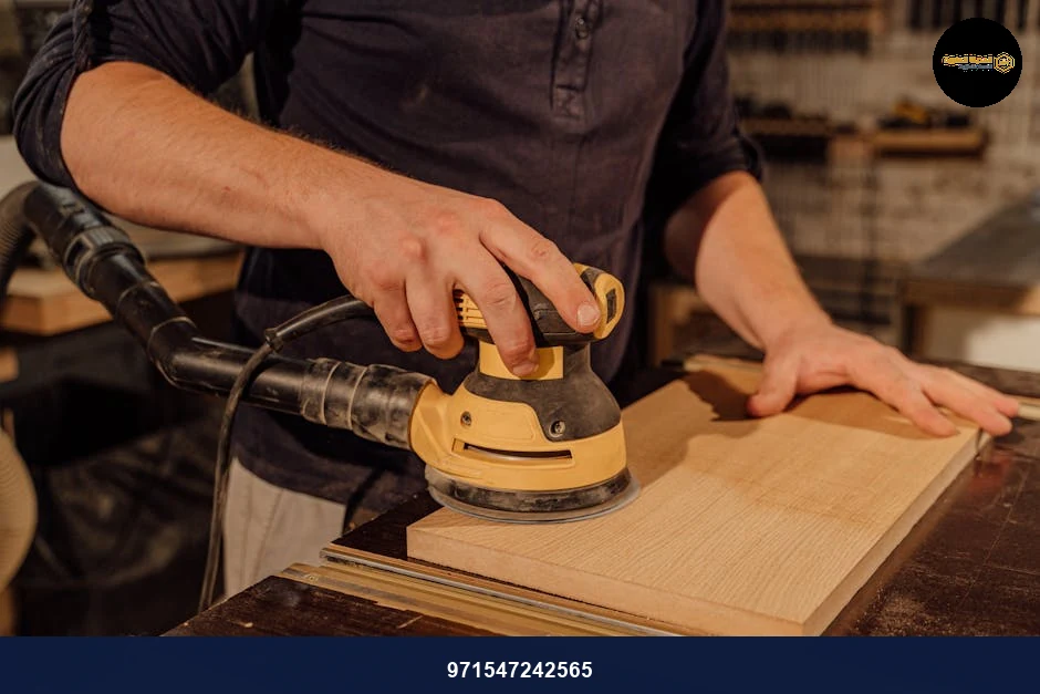 Carpenter using an electric sander on a wooden board in a workshop, showcasing craftsmanship.
