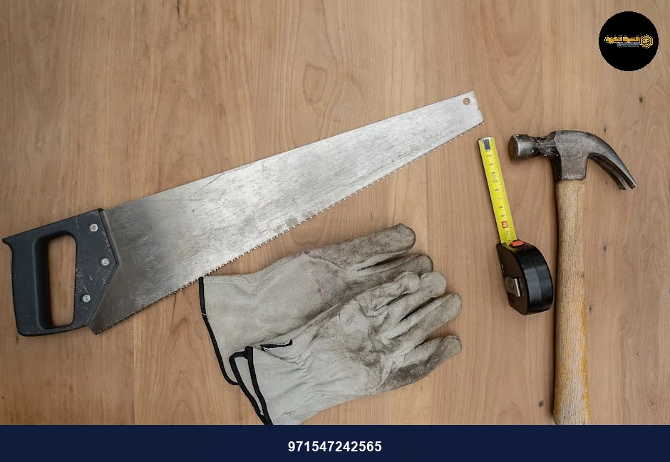 Flat lay of essential carpentry tools including a saw, hammer, and tape measure on wooden surface.