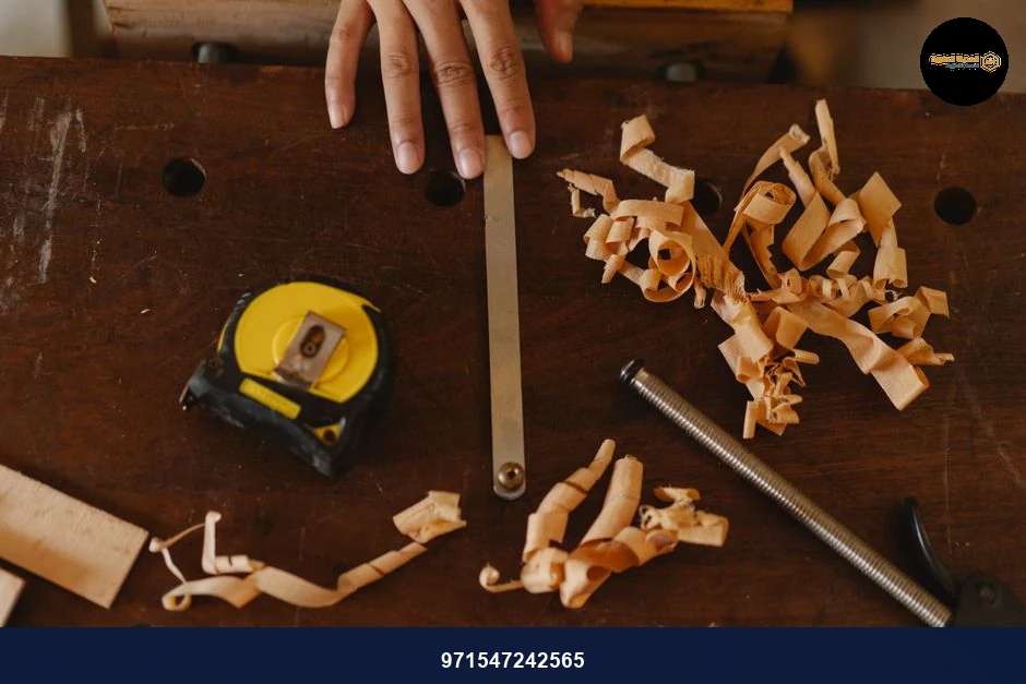 From above of crop anonymous woodworker with assorted instruments and wooden shavings in workshop
