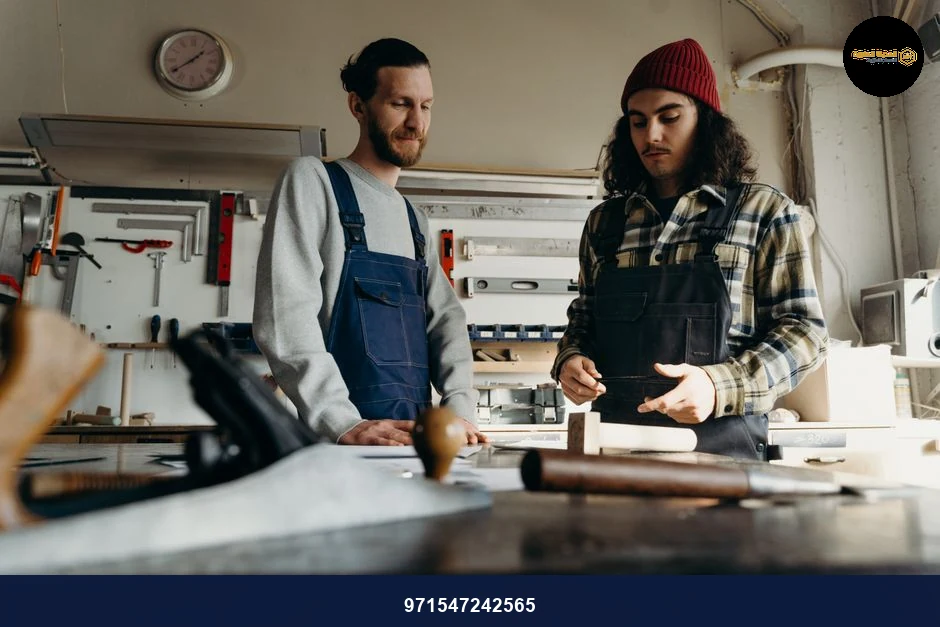 Two male carpenters working together in a well-equipped workshop.