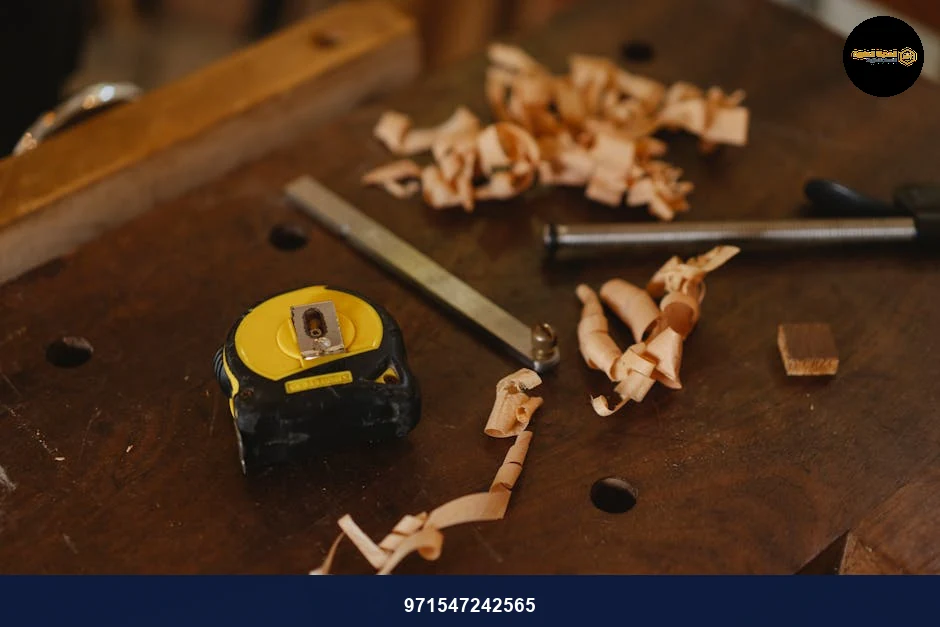 From above of tape measure near metal carpentry instruments with wooden shavings in workshop