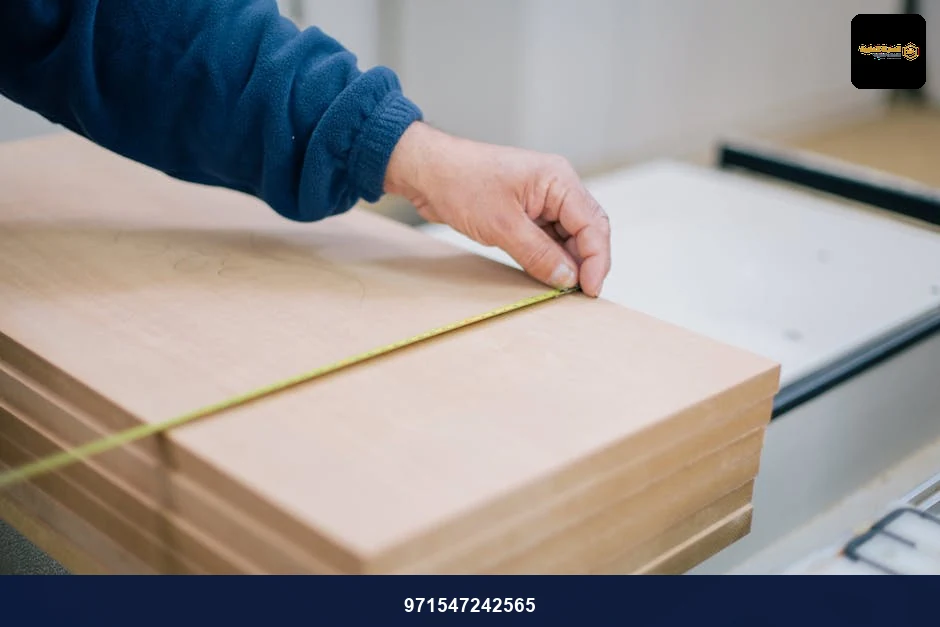 Close-up of a carpenter's hand using a tape measure to measure wooden planks indoors. Close-up of a carpenter's hand using a tape measure to measure wooden planks indoors.