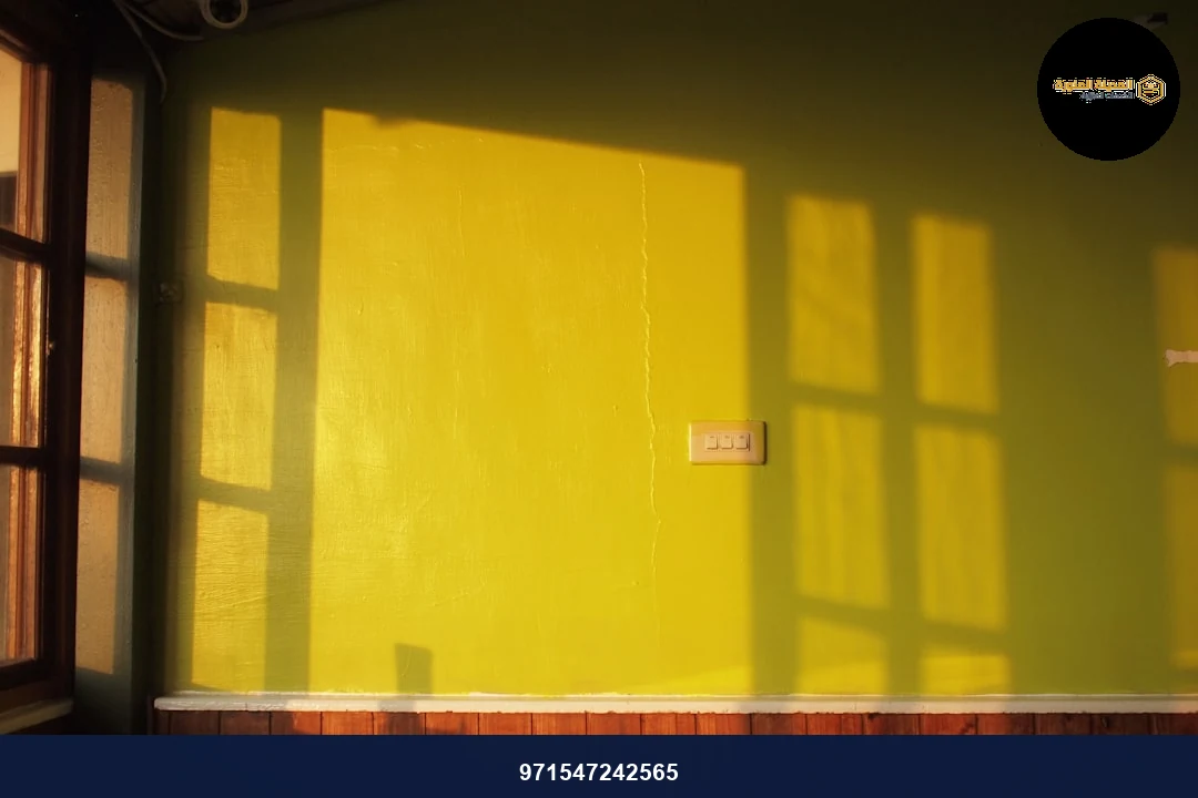 brown wooden bench beside yellow wall