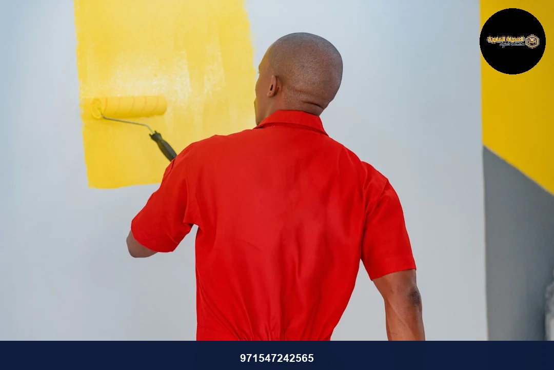 a man painting a wall with yellow paint