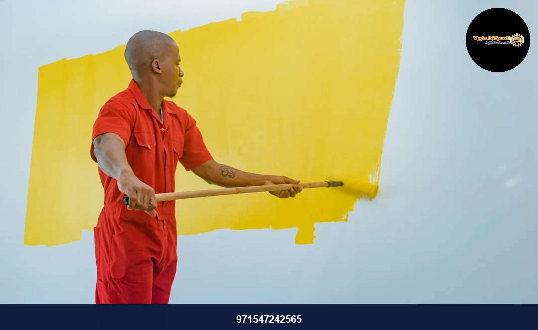 a man painting a wall with yellow paint
