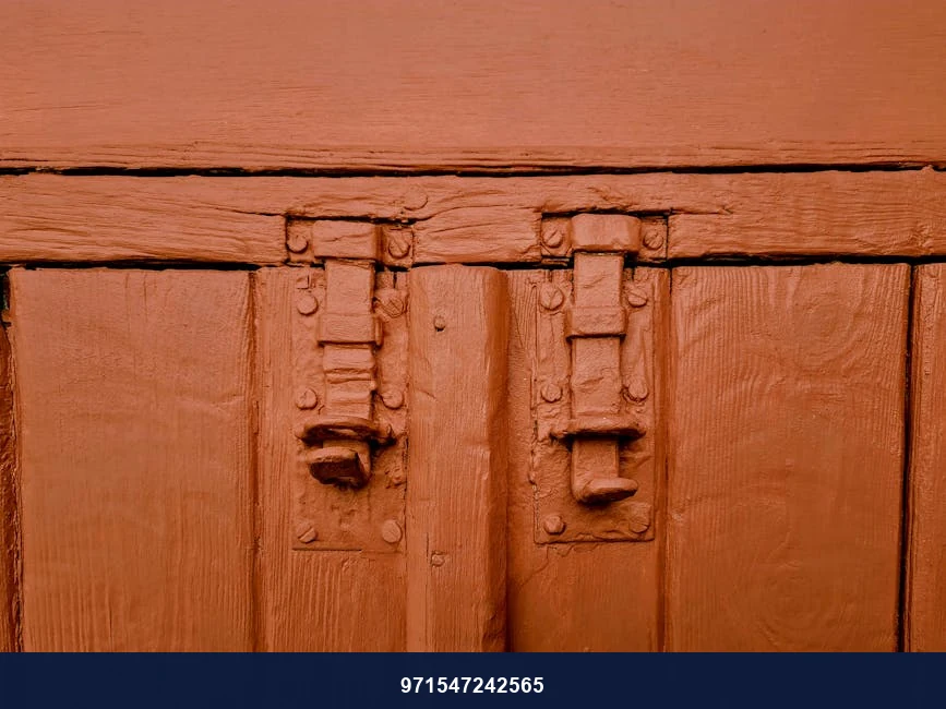 Close-up of a vintage red-painted wooden door with metal latches in Nicosia, Cyprus.